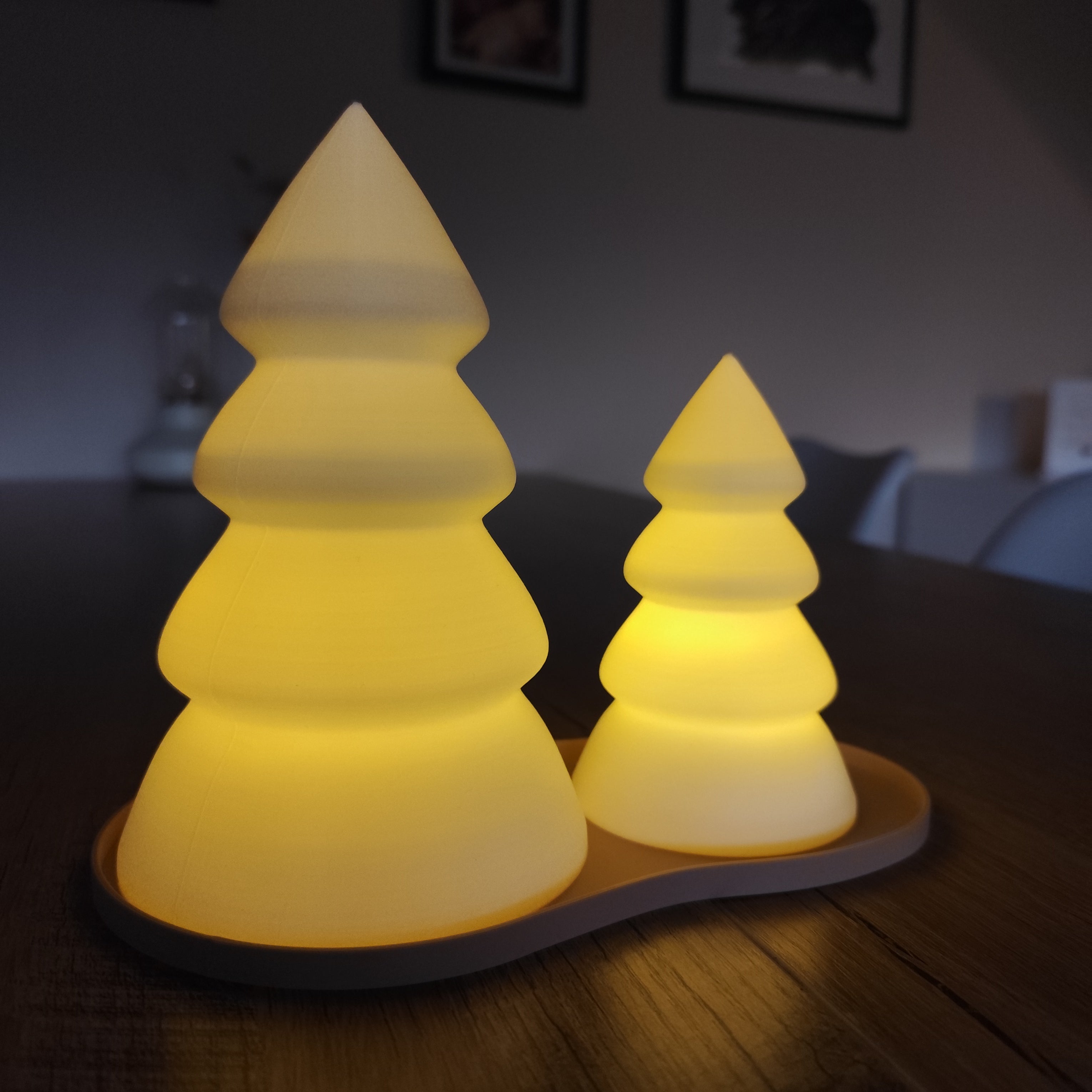 Two pyramid-shaped night lights on a wooden surface with a blurred background