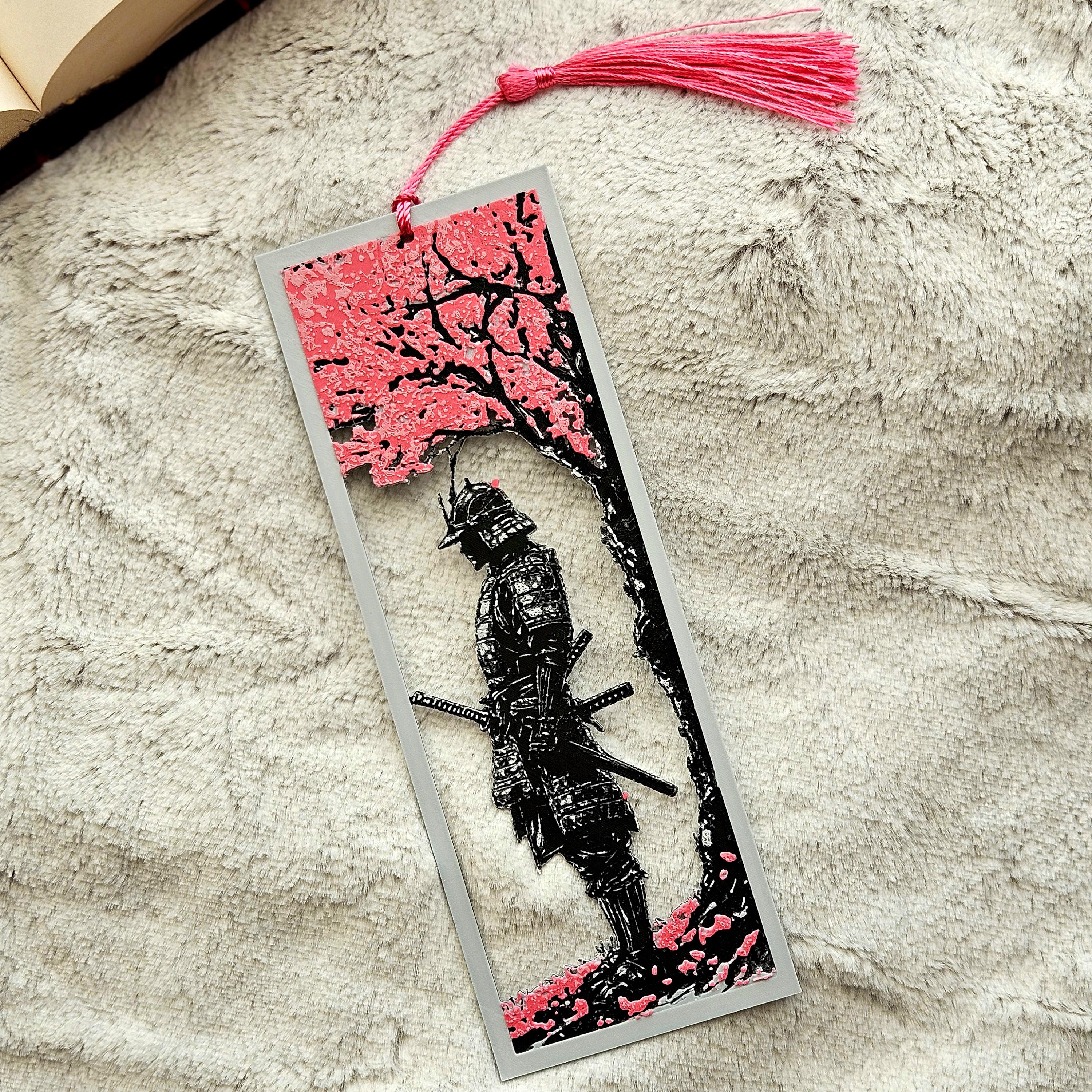 Bookmark with samurai design and pink cherry blossoms on a textured surface