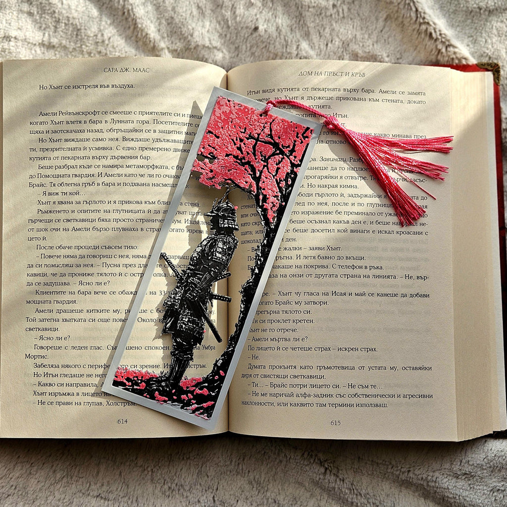 Open book with a decorative bookmark featuring a tree and black figure on a textured surface.