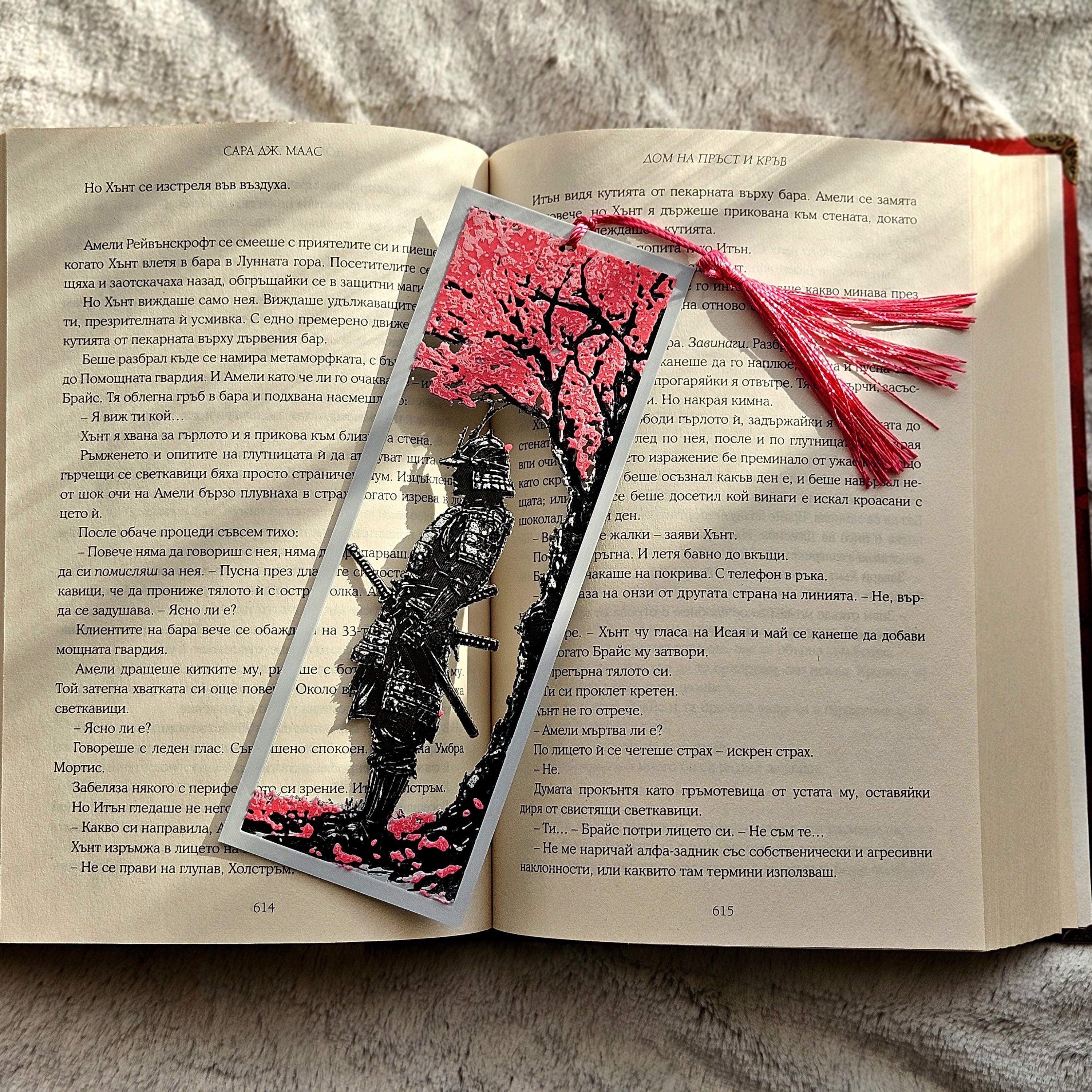 Open book with a decorative bookmark featuring a tree and black figure on a textured surface.