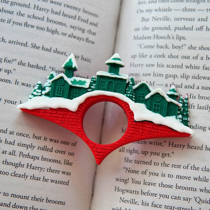 Decorative bookmark shaped like a snowy village on an open book