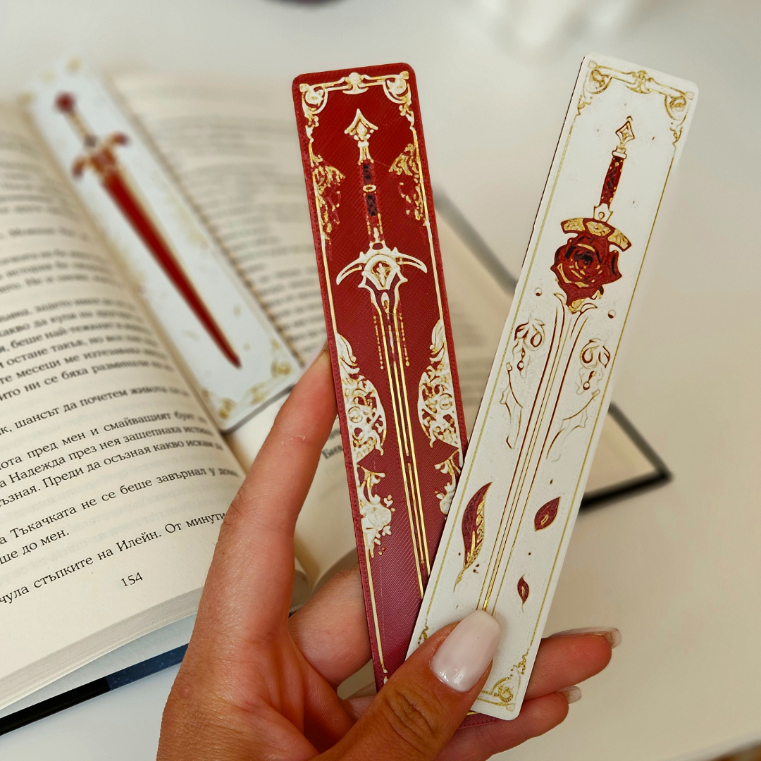 Decorative bookmarks with sword designs held over an open book.