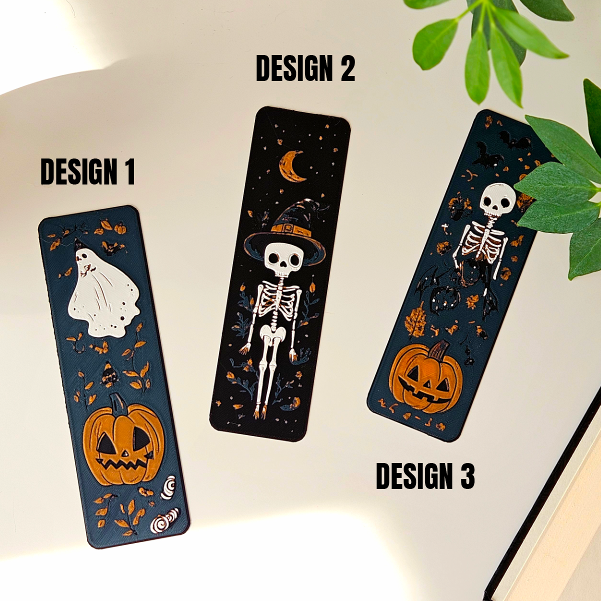 Three Halloween-themed bookmarks with designs of a ghost, skeleton, and pumpkin on a white background.