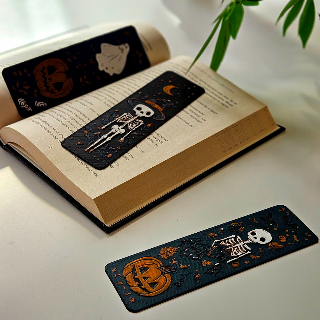 Open book with Halloween-themed bookmarks on a white surface