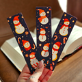 Three Christmas-themed bookmarks with snowmen on a dark blue background held by a hand.