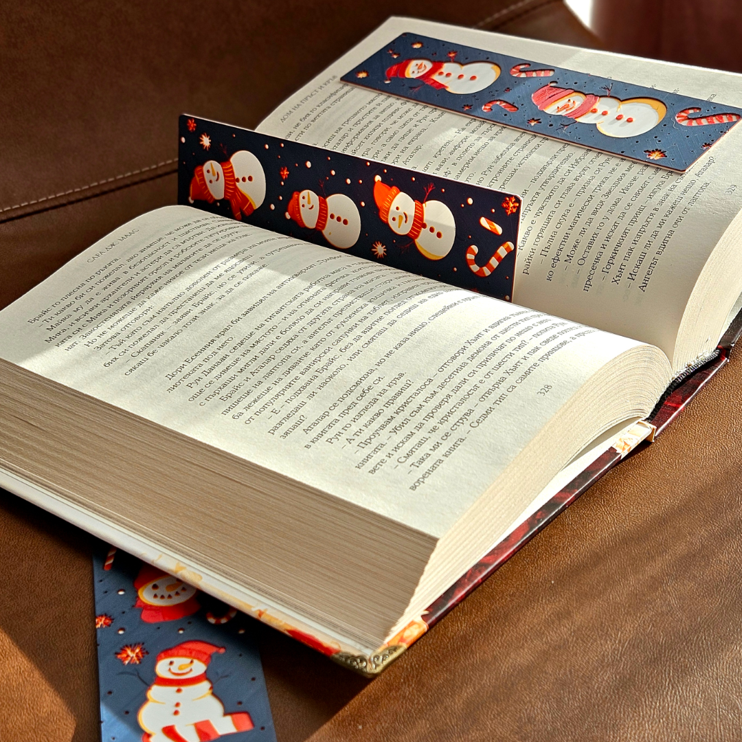 Open book with Christmas-themed bookmarks on a wooden surface