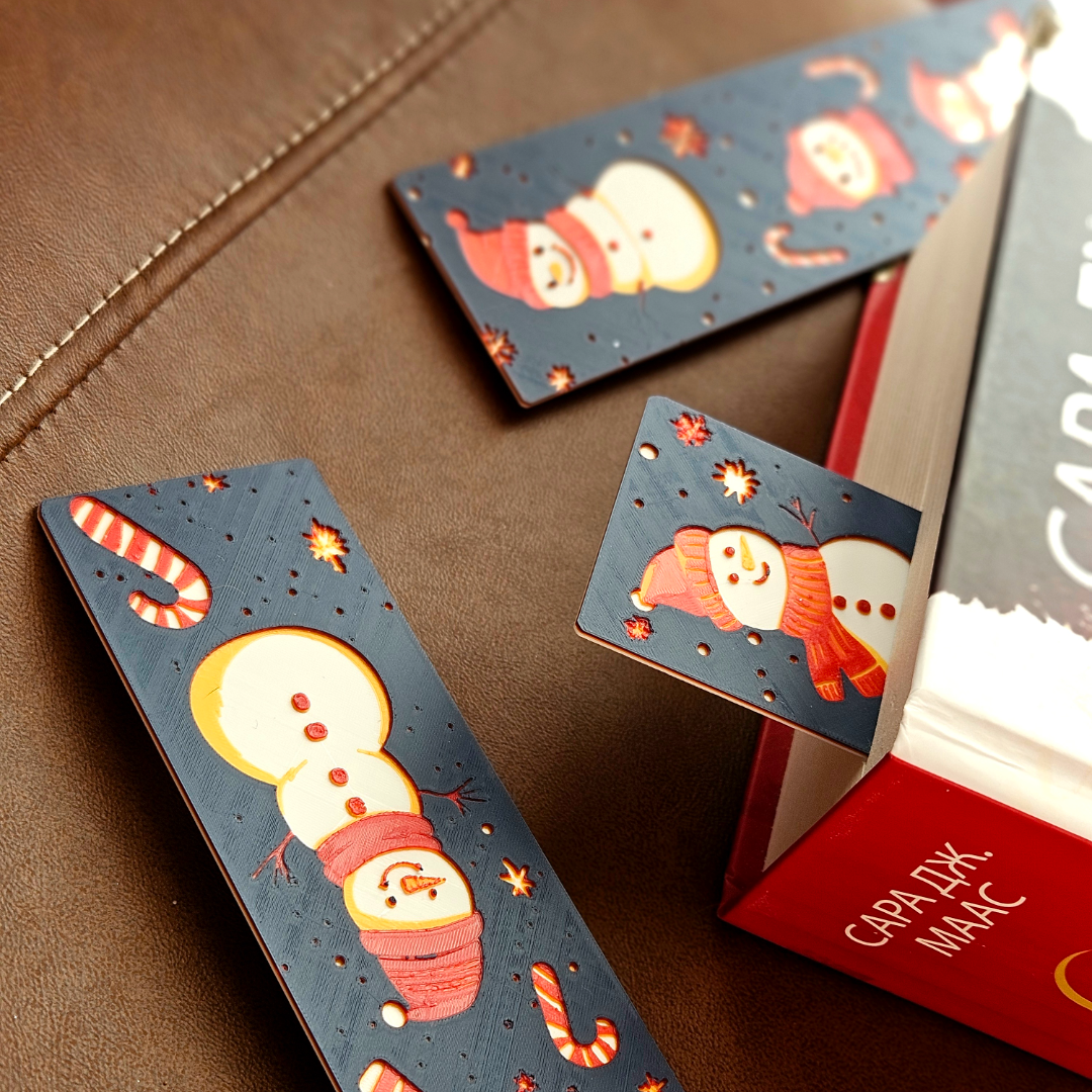 Decorative bookmarks with snowman designs on a brown surface