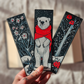 Three decorative bookmarks featuring a polar bear, flowers, and a sword.