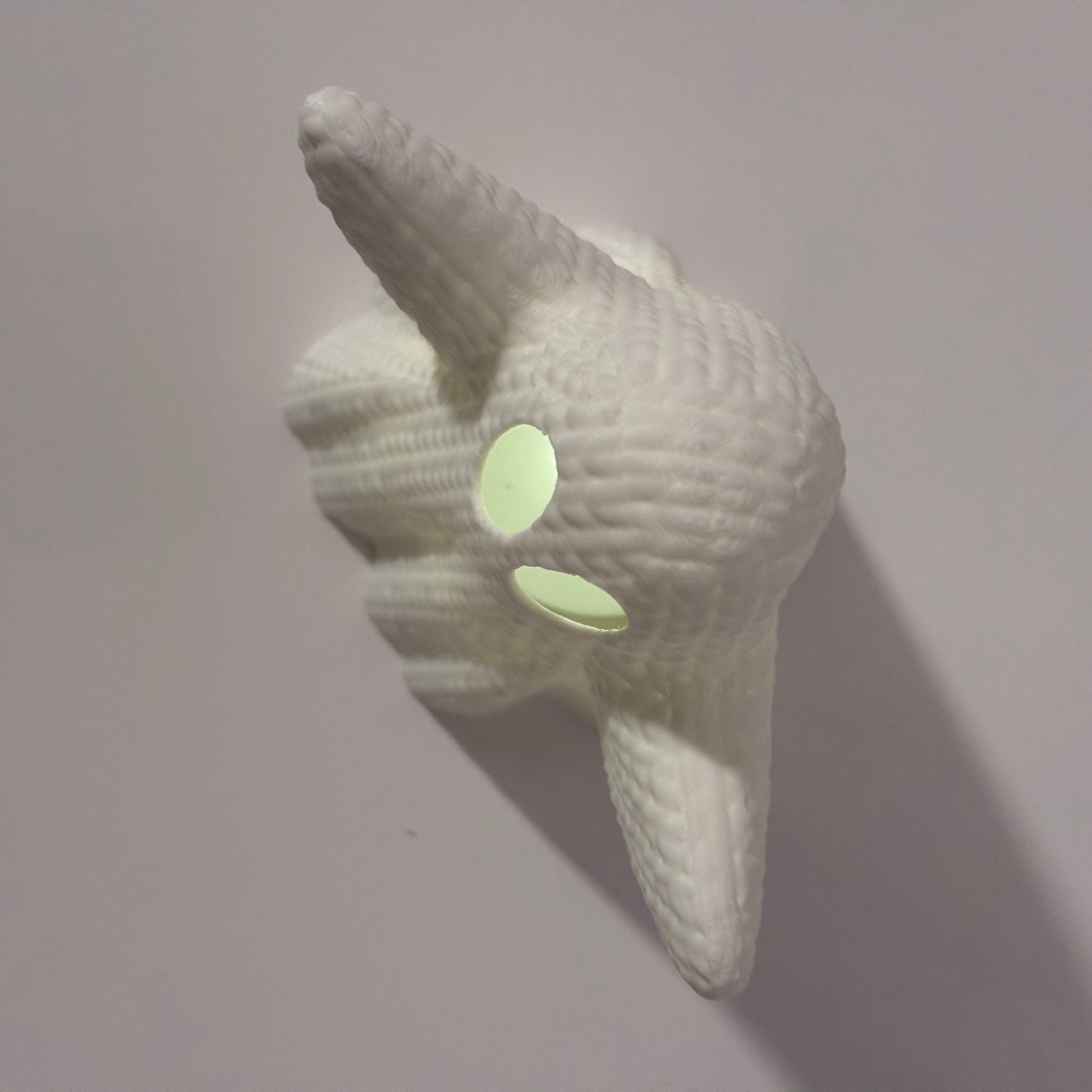 White knitted ghost with glowing eyes on a light gray background