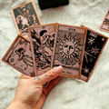 Hand holding tarot cards with detailed artwork on a textured surface