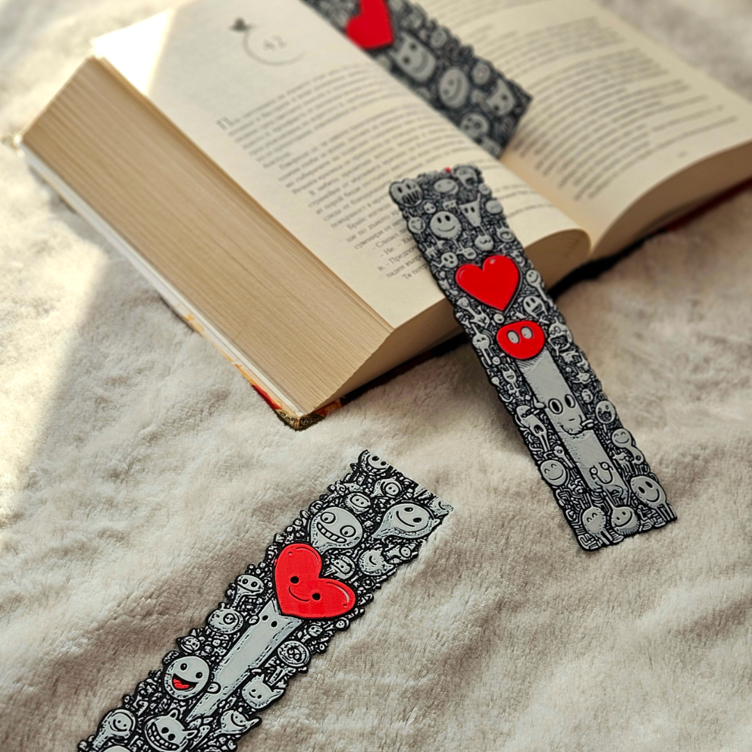 Decorative bookmarks with red hearts on a textured surface next to an open book.
