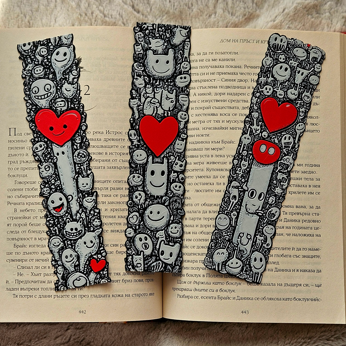 Three decorative bookmarks with cartoon characters and red hearts on an open book.