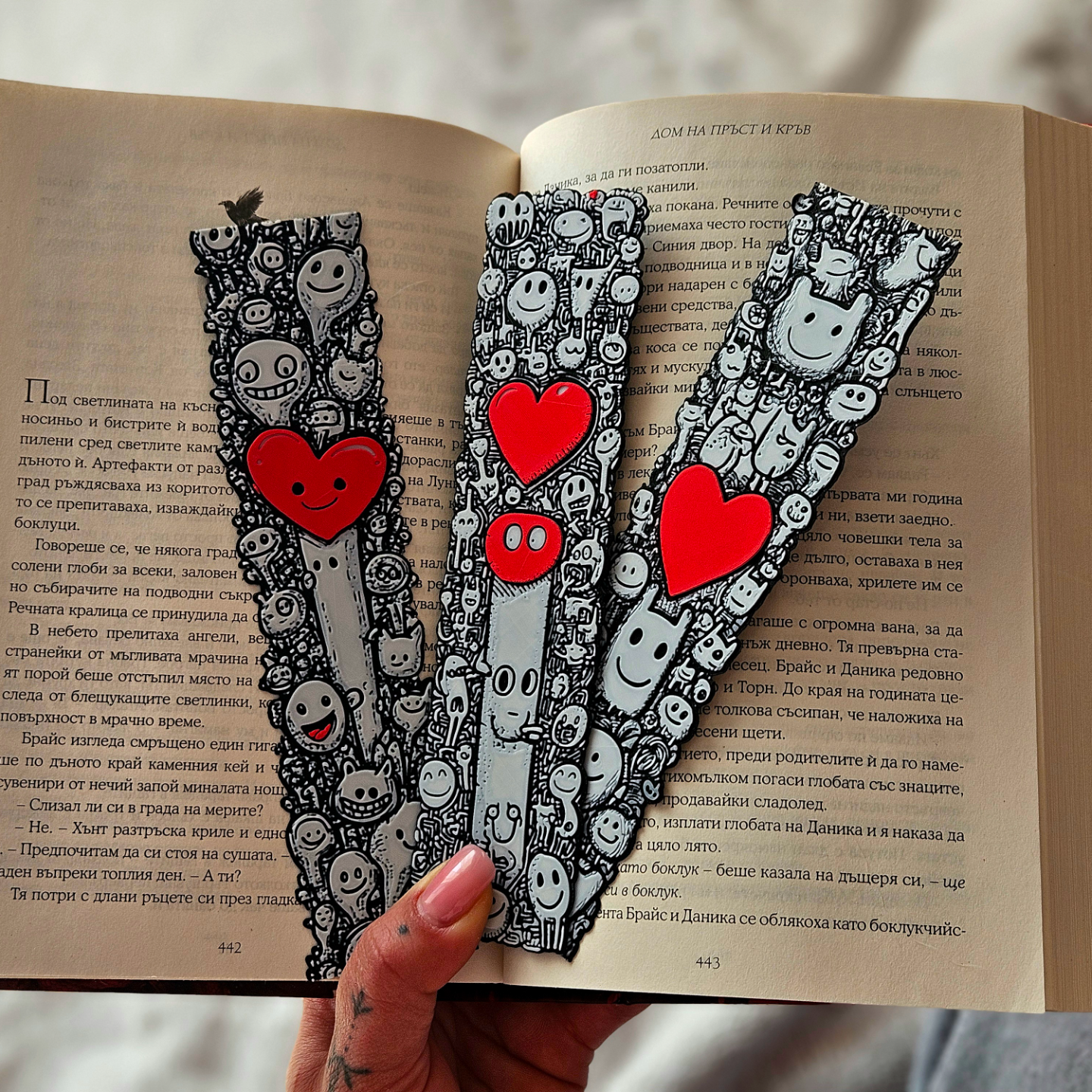 Three decorative bookmarks with cartoon characters and red hearts on an open book.