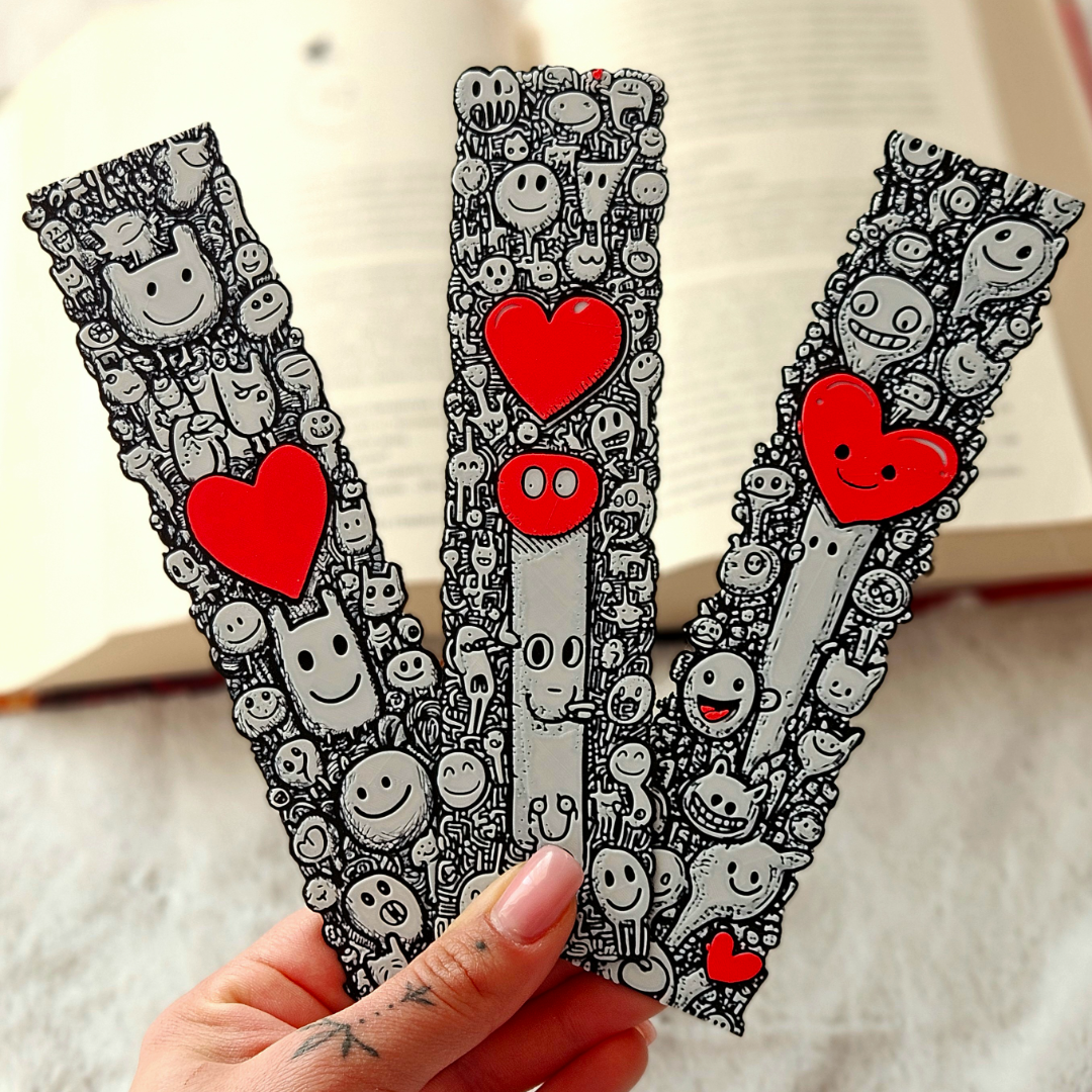Three letter 'V' shaped bookmarks with cartoon characters and red hearts held by a hand.