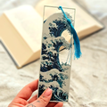 Bookmark with wave design held by a hand, with a blurred background