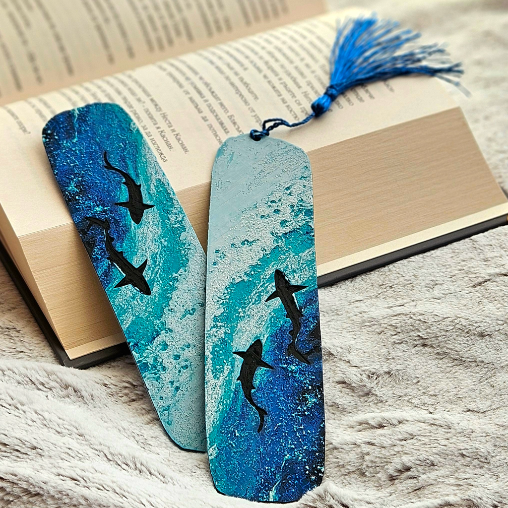 Two blue bookmarks with shark designs on a book