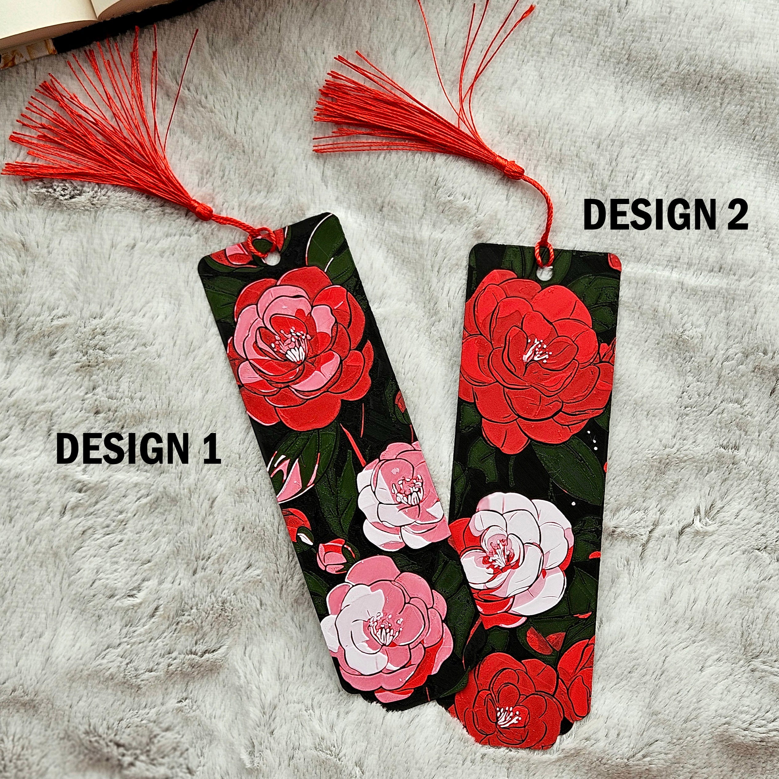 Two floral bookmarks with tassels on a textured surface, labeled 'Design 1' and 'Design 2'.