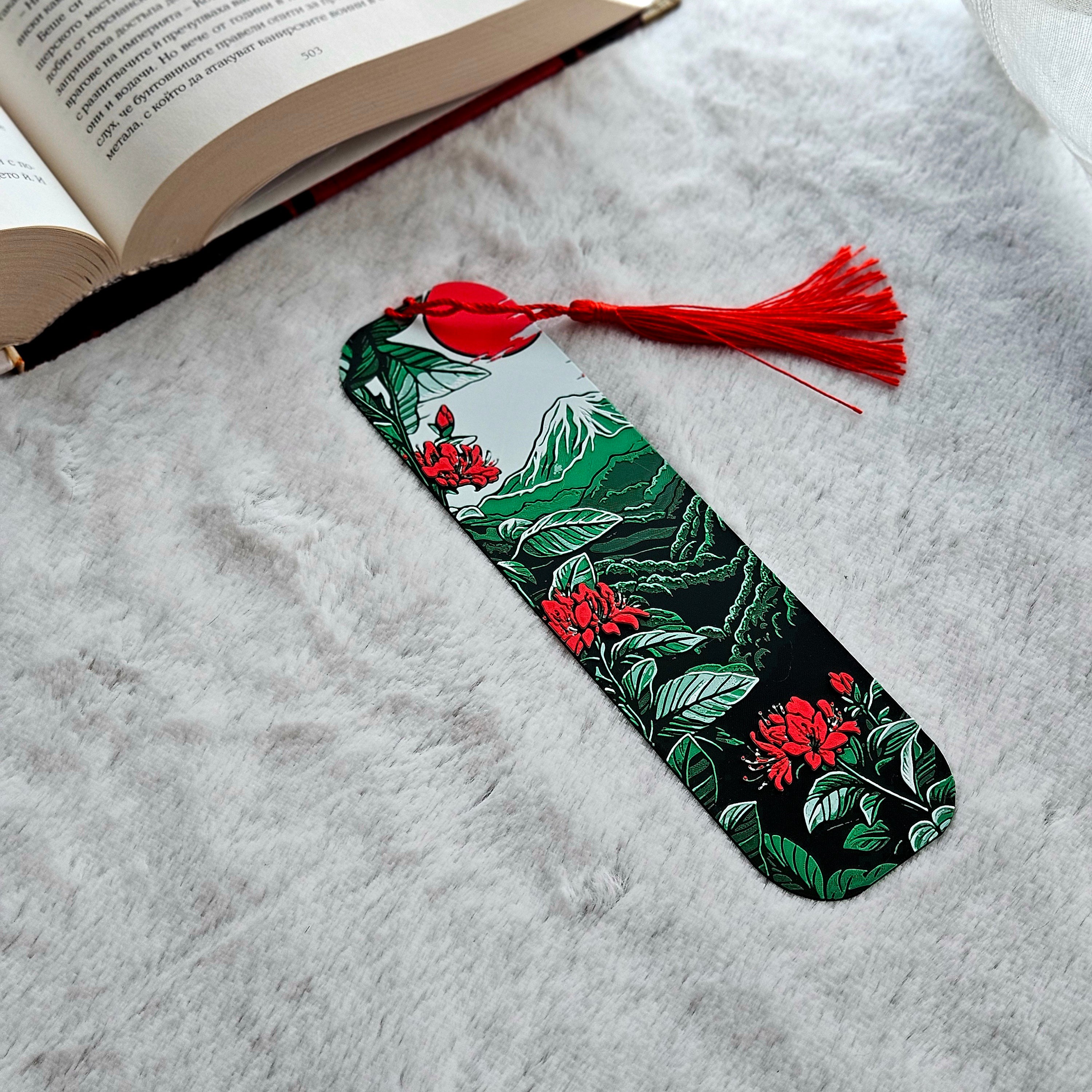 Decorative bookmark with floral design and red tassel on a textured surface