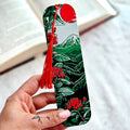 Hand holding a decorative bookmark with tassel against a blurred background