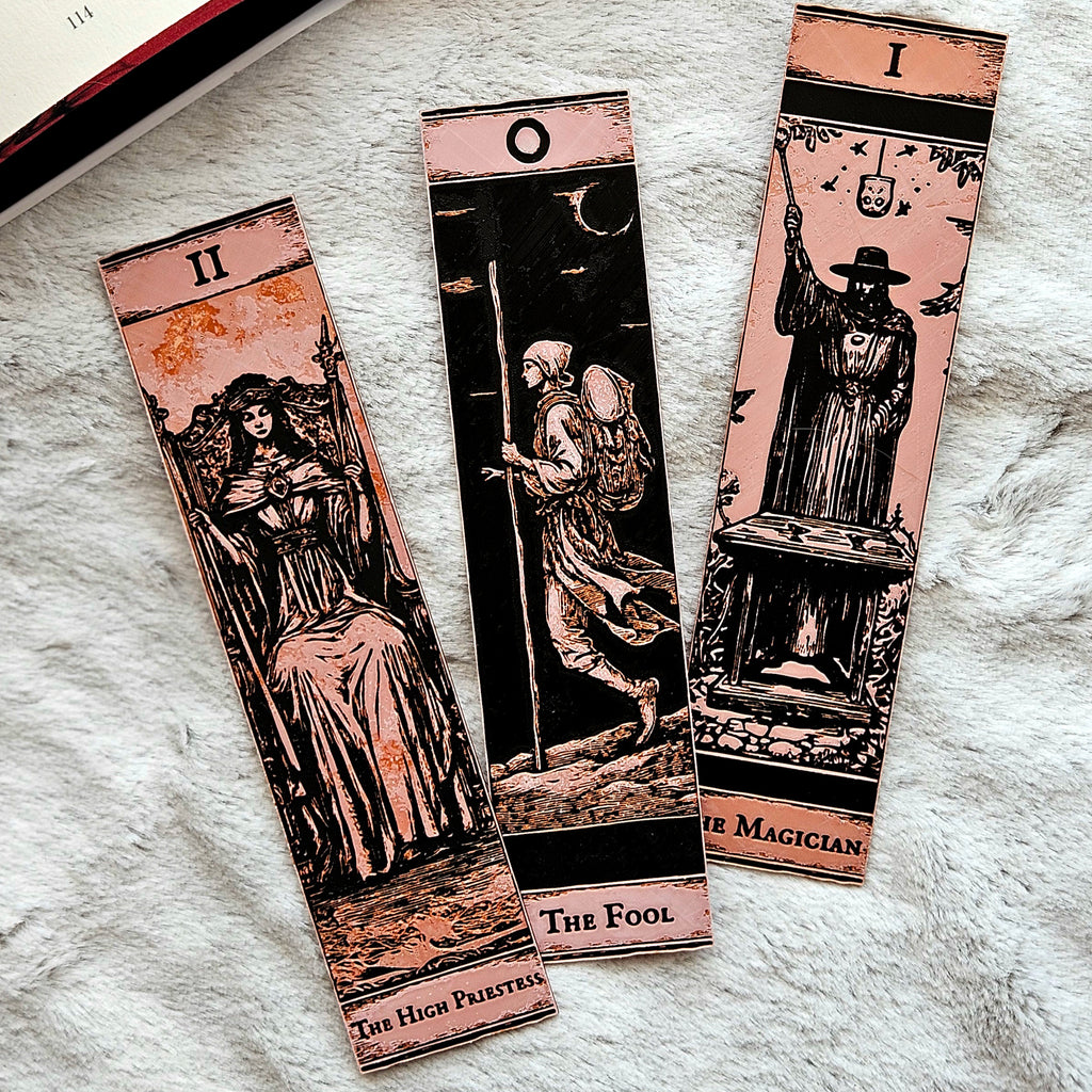 Three tarot card bookmarks on a textured surface
