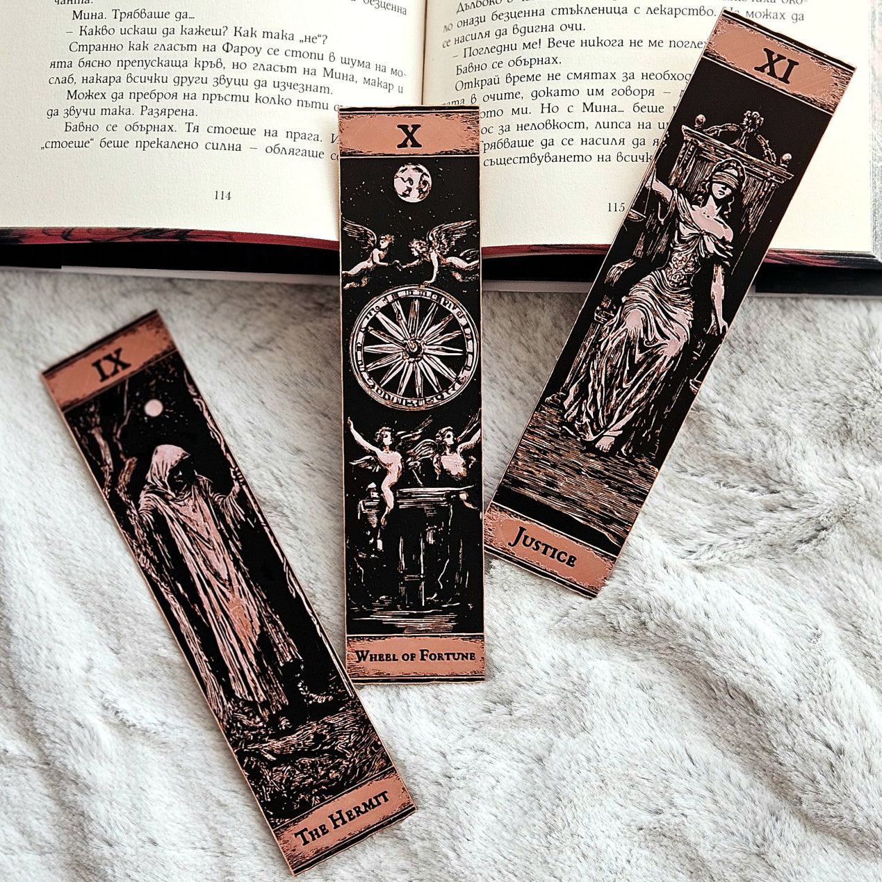 Three tarot card bookmarks on a textured surface with an open book in the background.