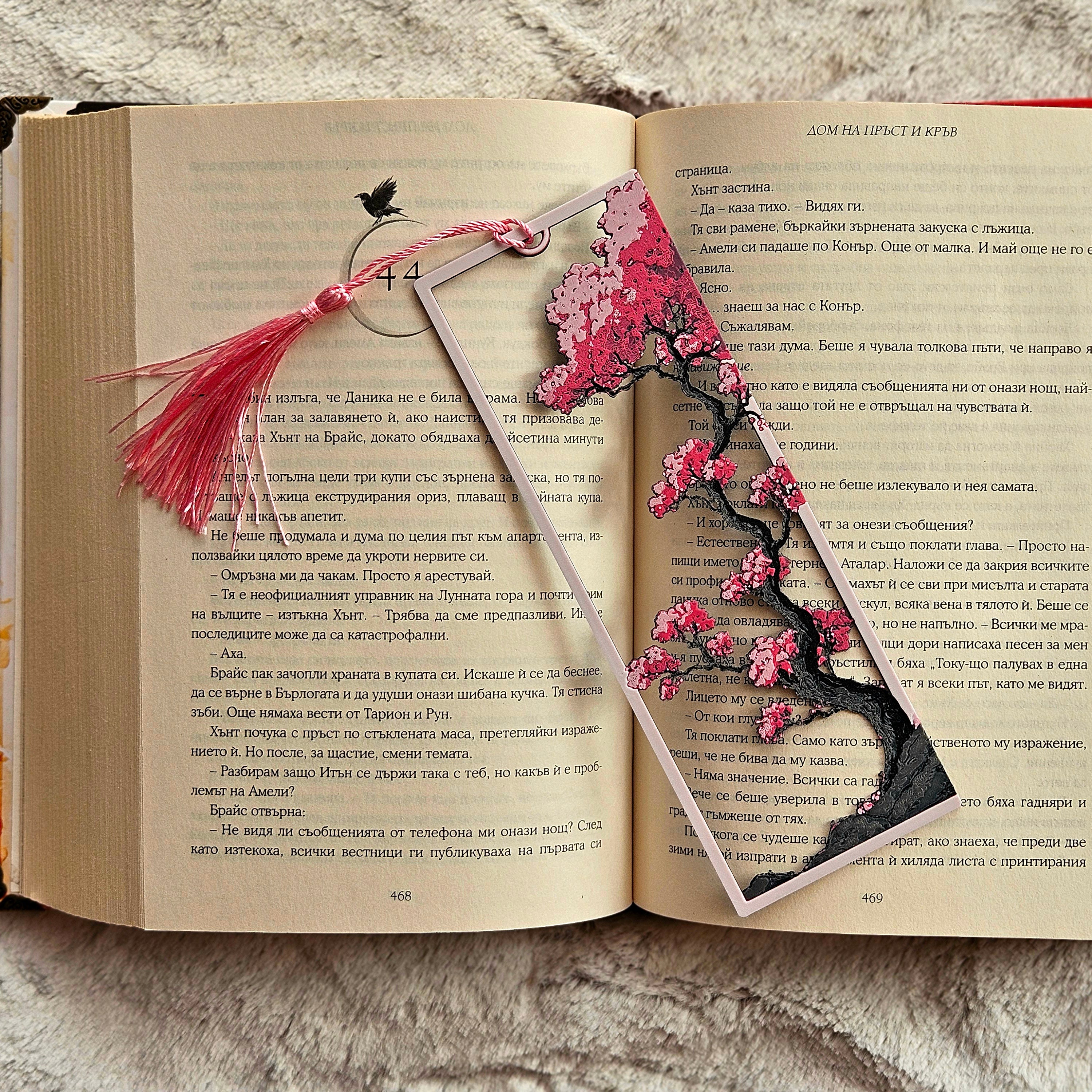 Decorative pink floral bookmark on an open book with a tassel.