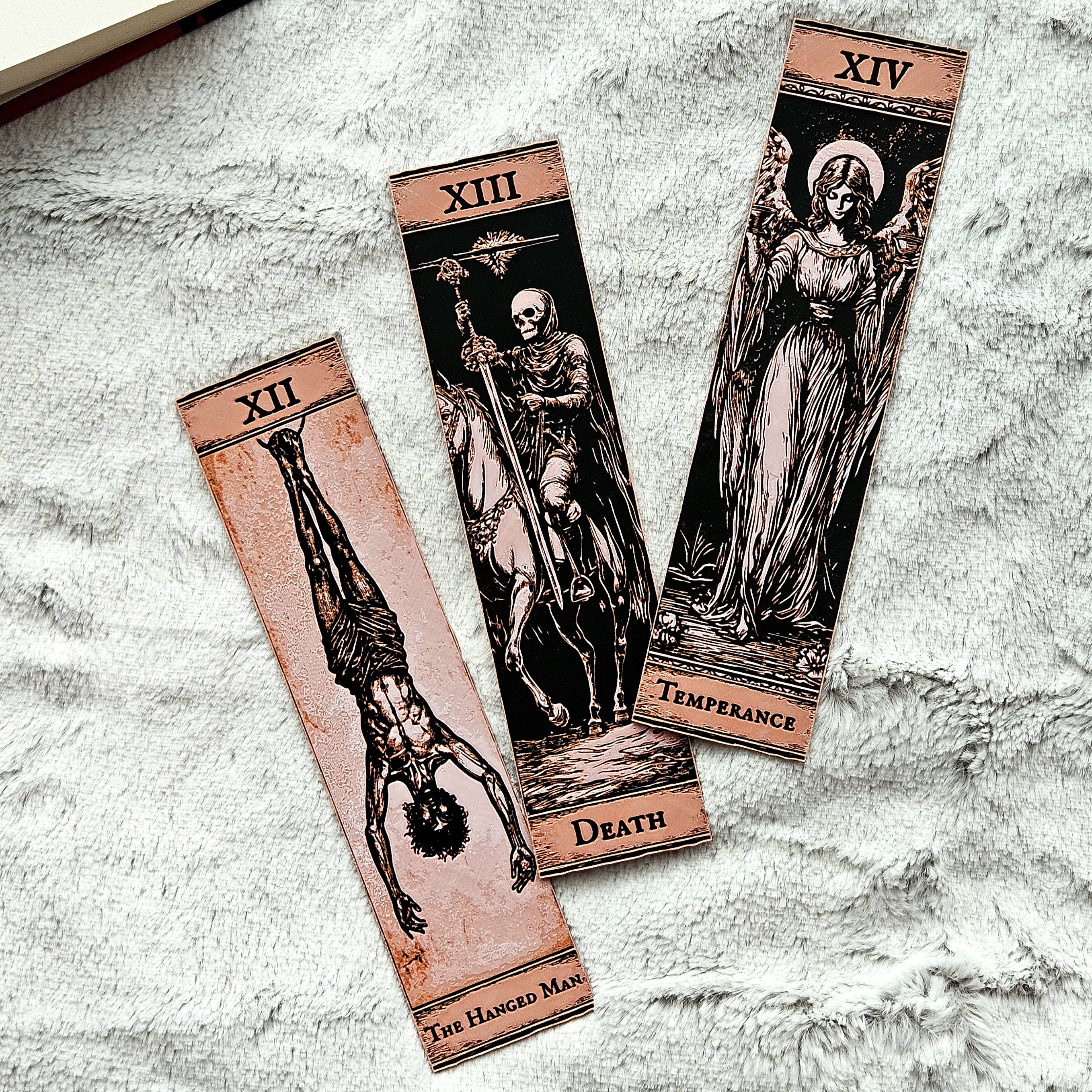 Three tarot cards labeled 'The Hanged Man', 'Death', and 'Temperance' on a textured surface.