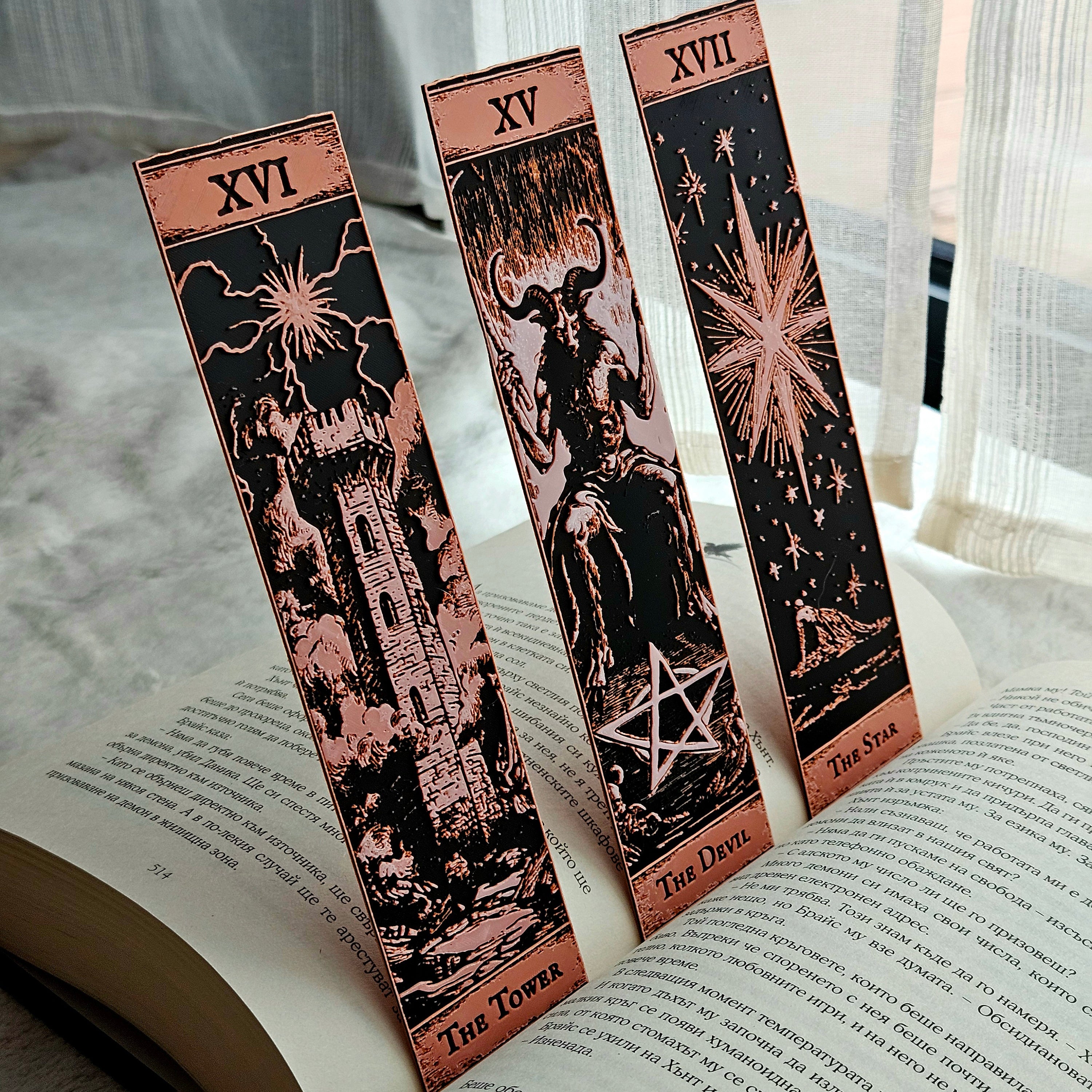 Three tarot card bookmarks on an open book with a neutral background