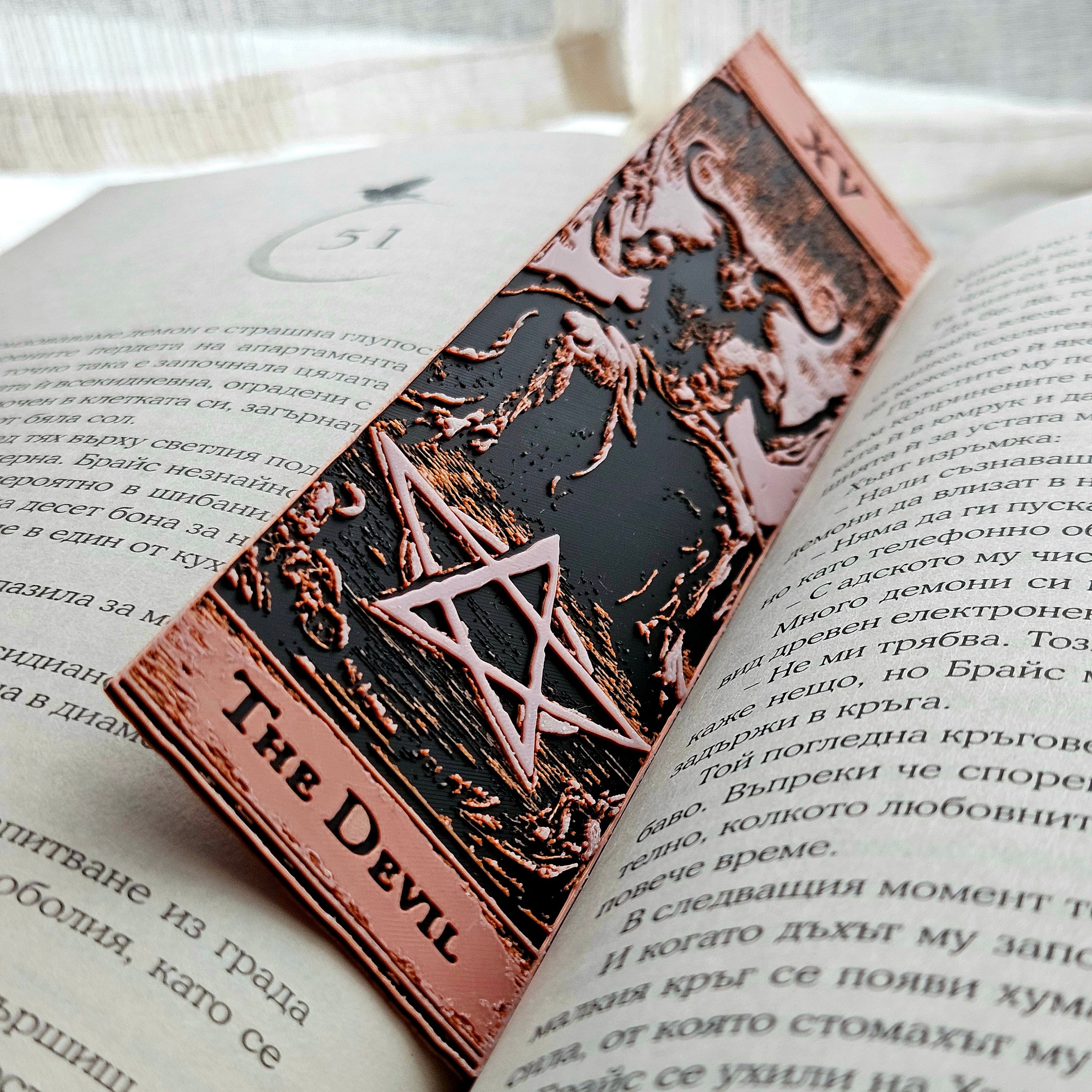 Decorative bookmark with 'The Devil' design on an open book