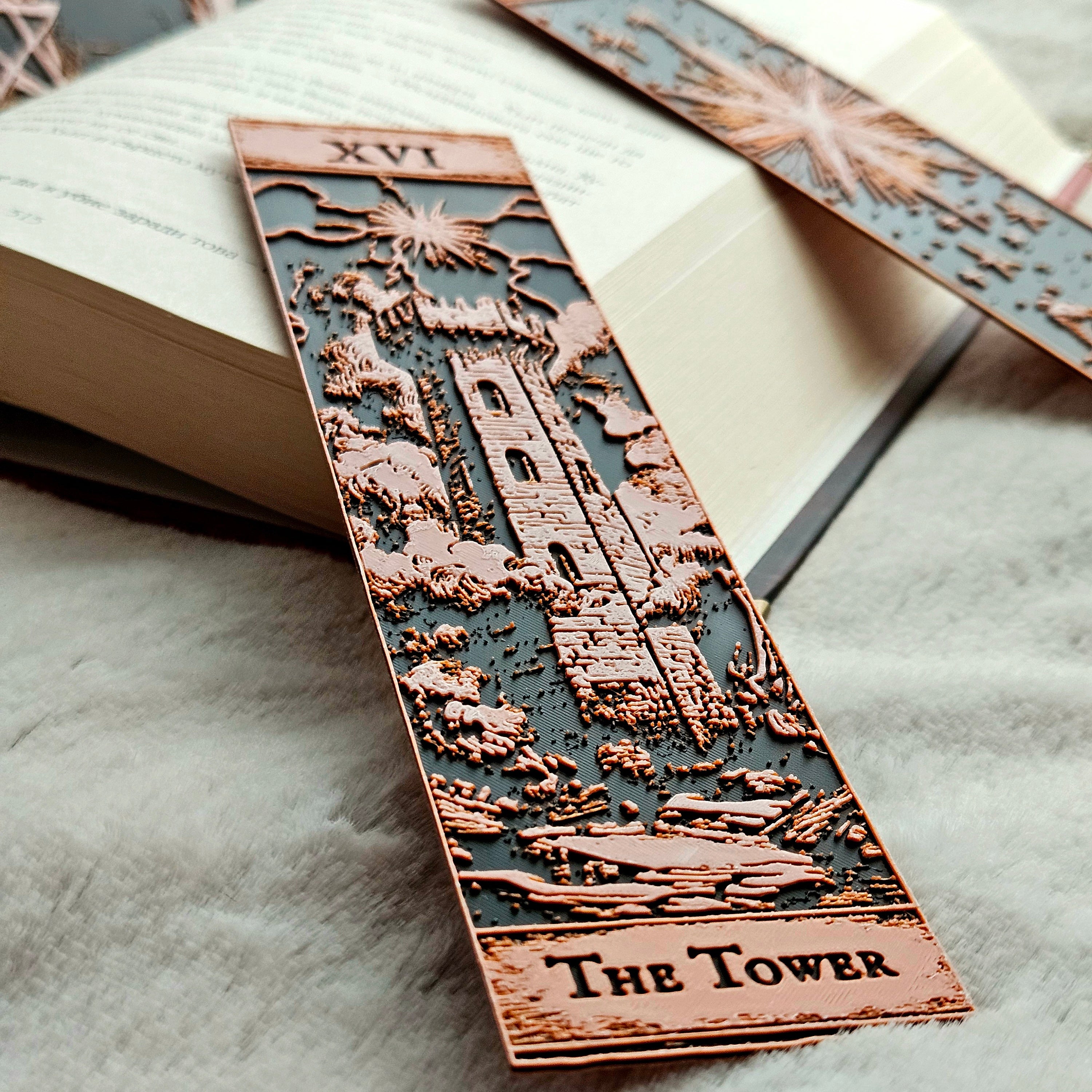 Decorative tarot card bookmark titled 'The Tower' on an open book.