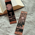 Two tarot card-style bookmarks on a textured surface with an open book in the background.