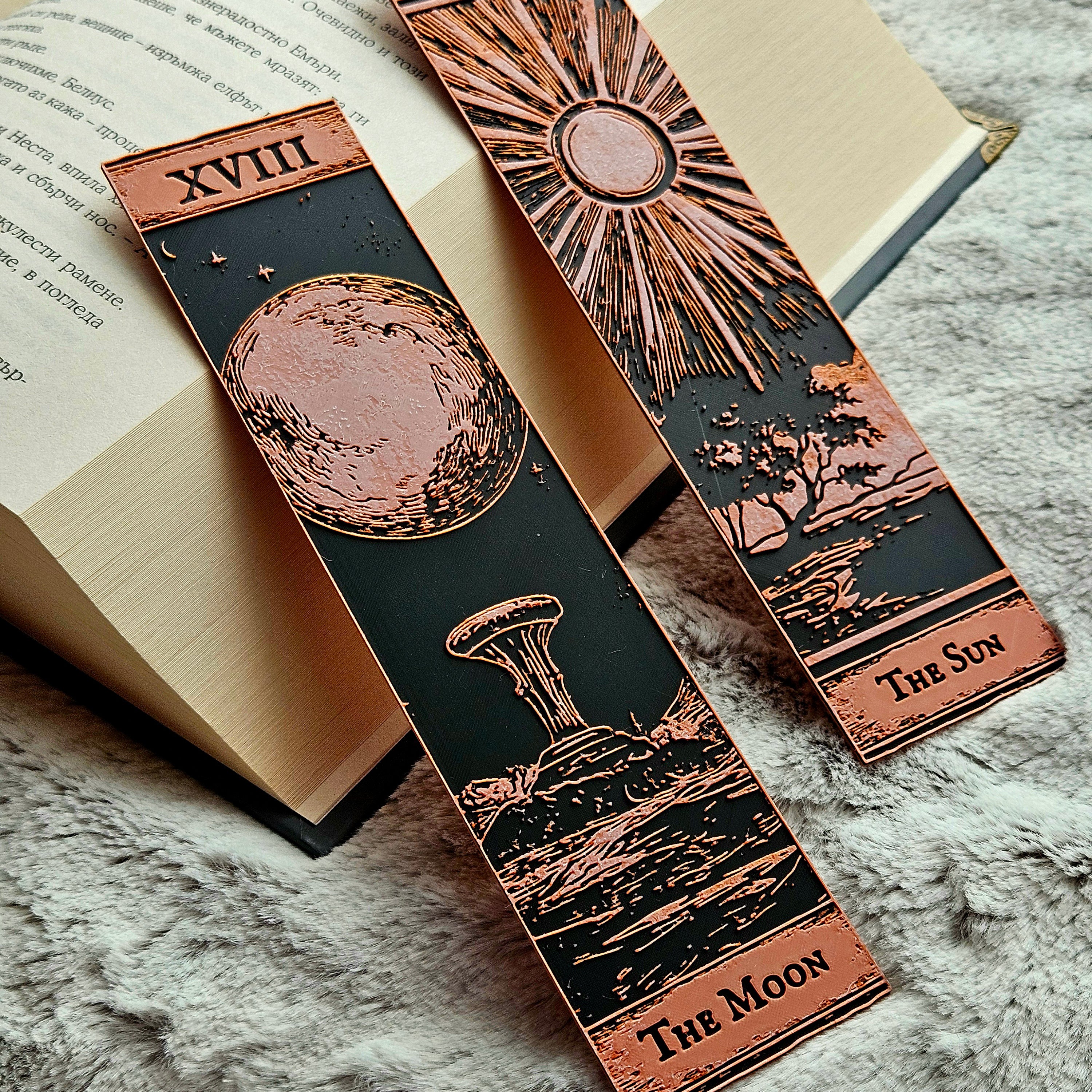 Two ornate bookmarks with celestial designs on an open book.