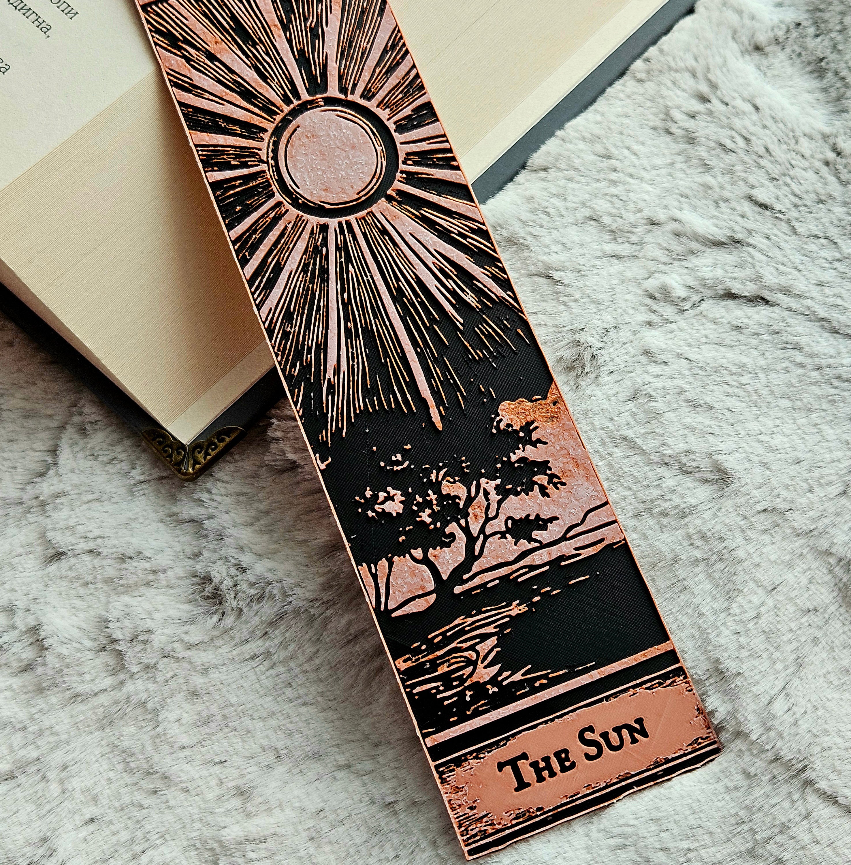 Decorative bookmark with sun design and 'The Sun' text on a textured surface