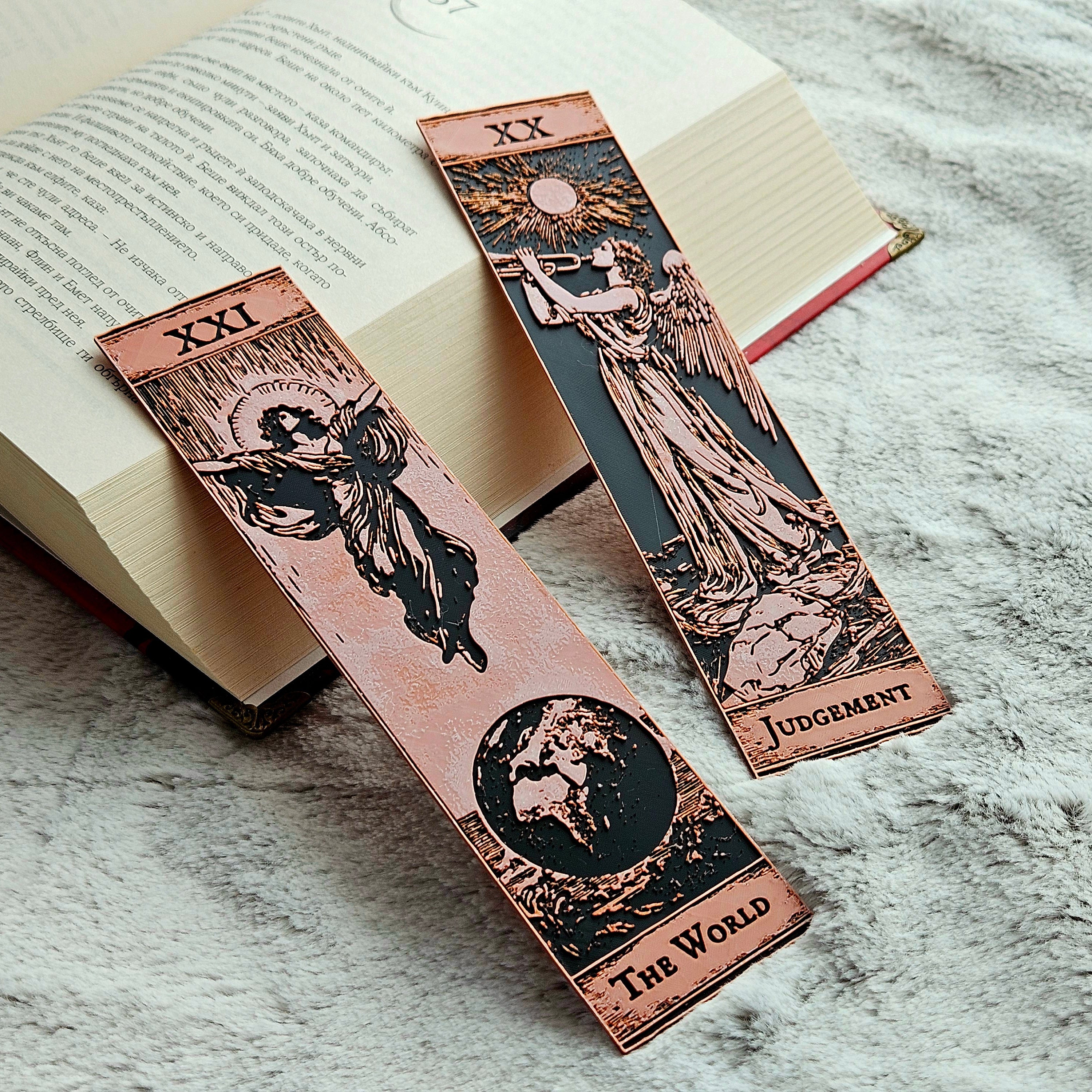 Two tarot card bookmarks on an open book with a marble surface.