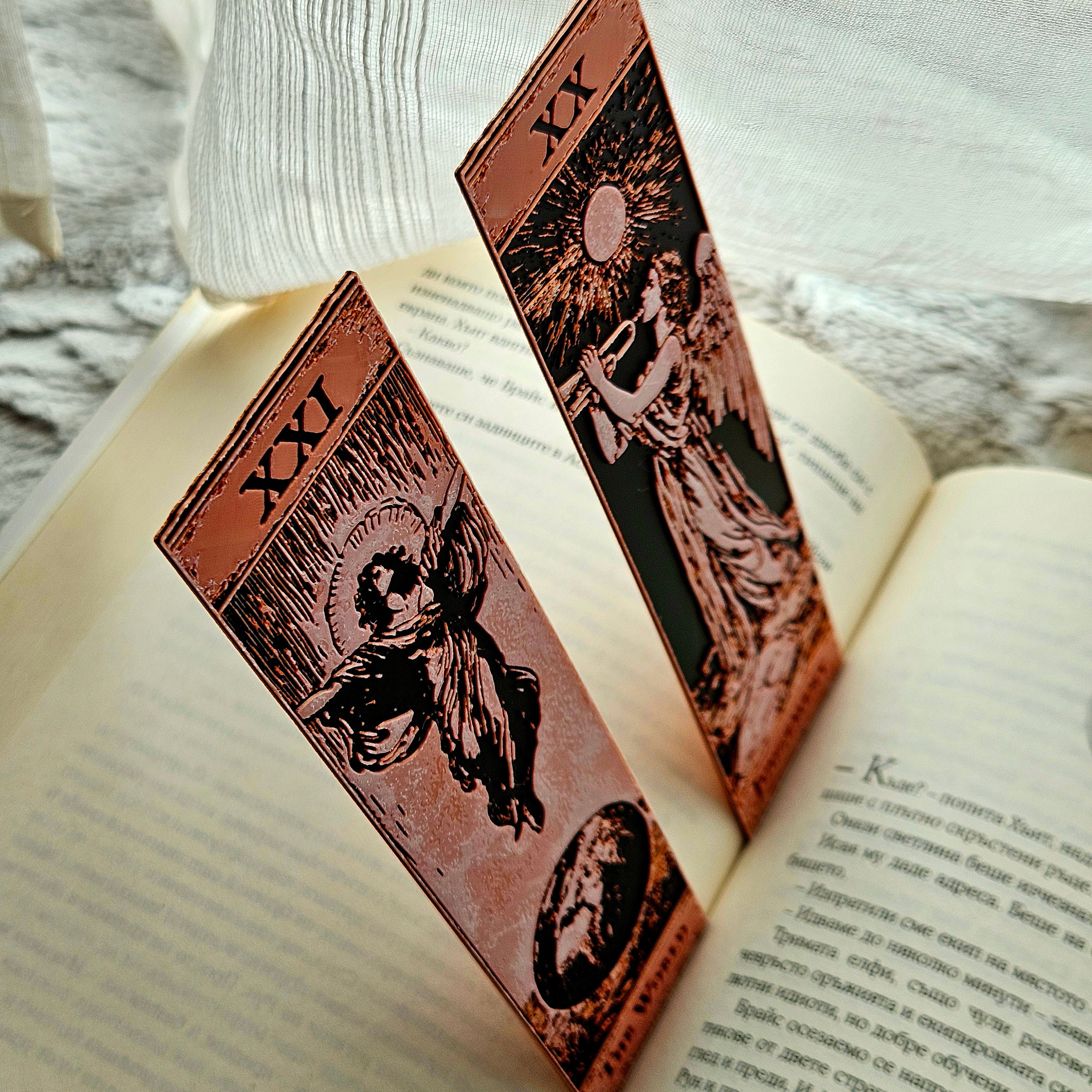 Two tarot card bookmarks on an open book with a textured background.
