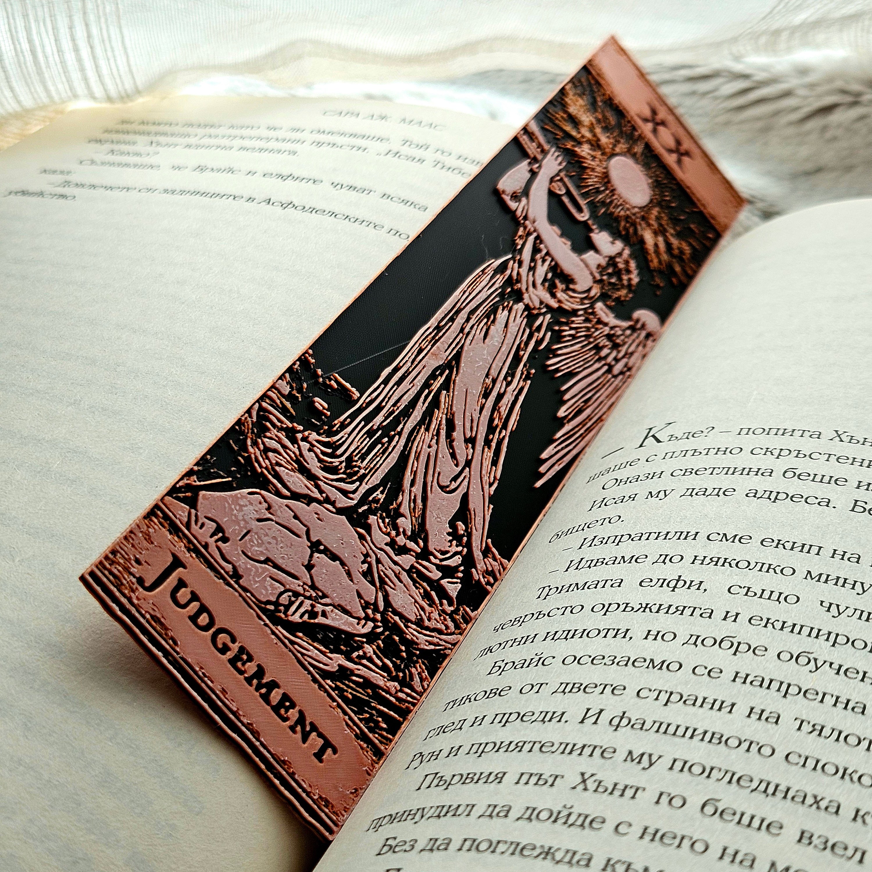 Book with a bronze bookmark featuring an illustration of a figure labeled 'Judgement' on a light background.