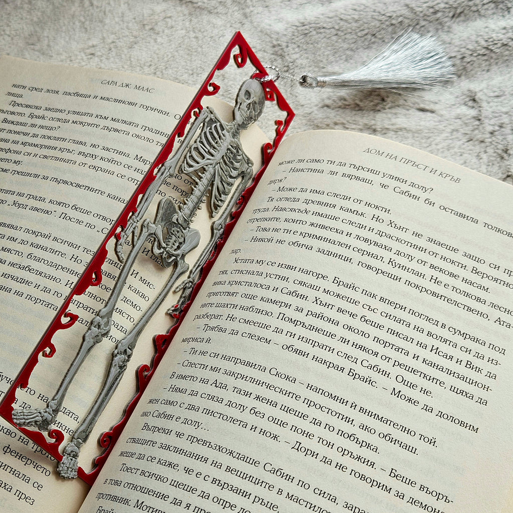 Skeleton bookmark on an open book with a decorative red border.