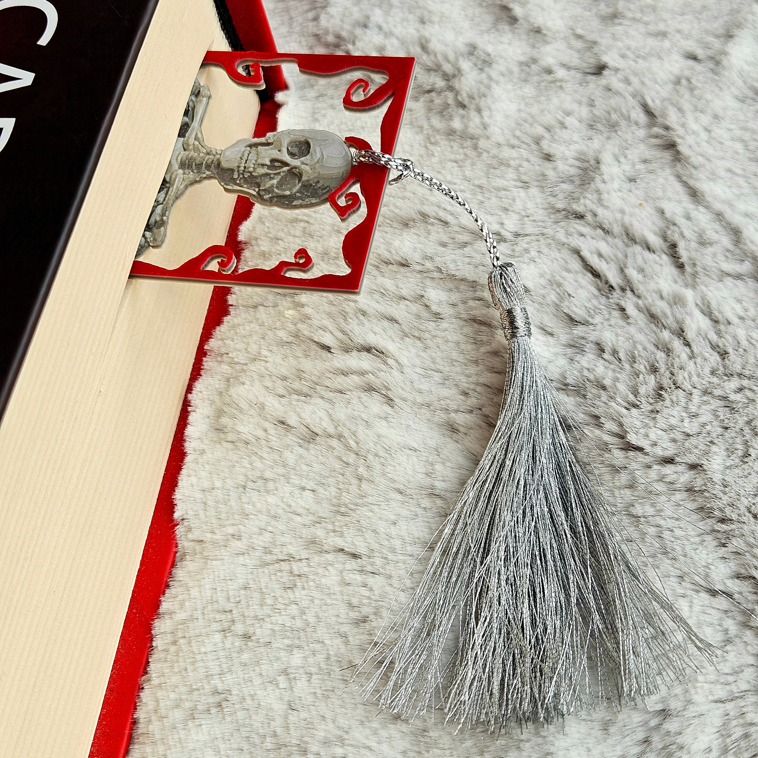 Decorative bookmark with skull design and tassel on a textured surface