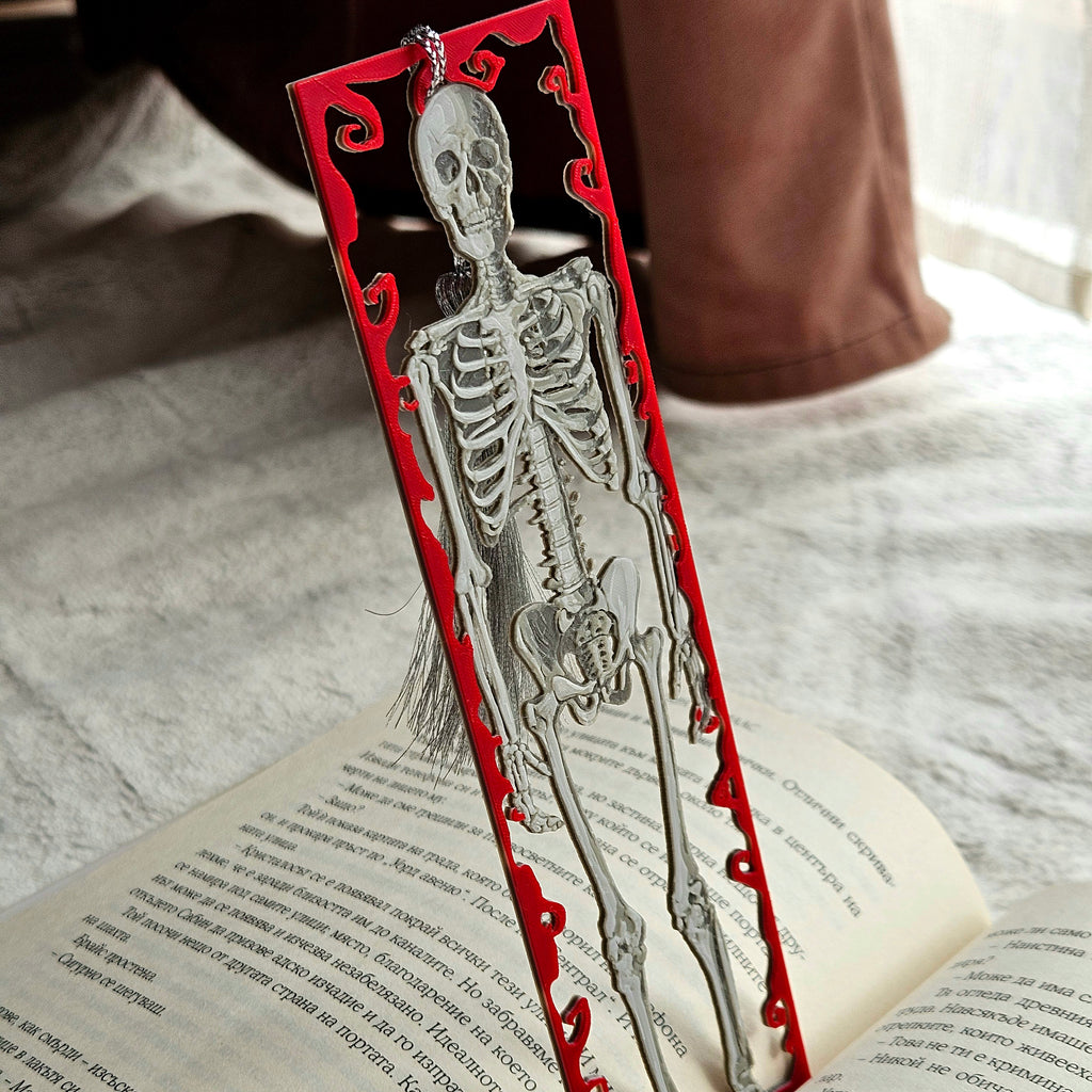 Skeletal design bookmark on an open book with a red decorative border.