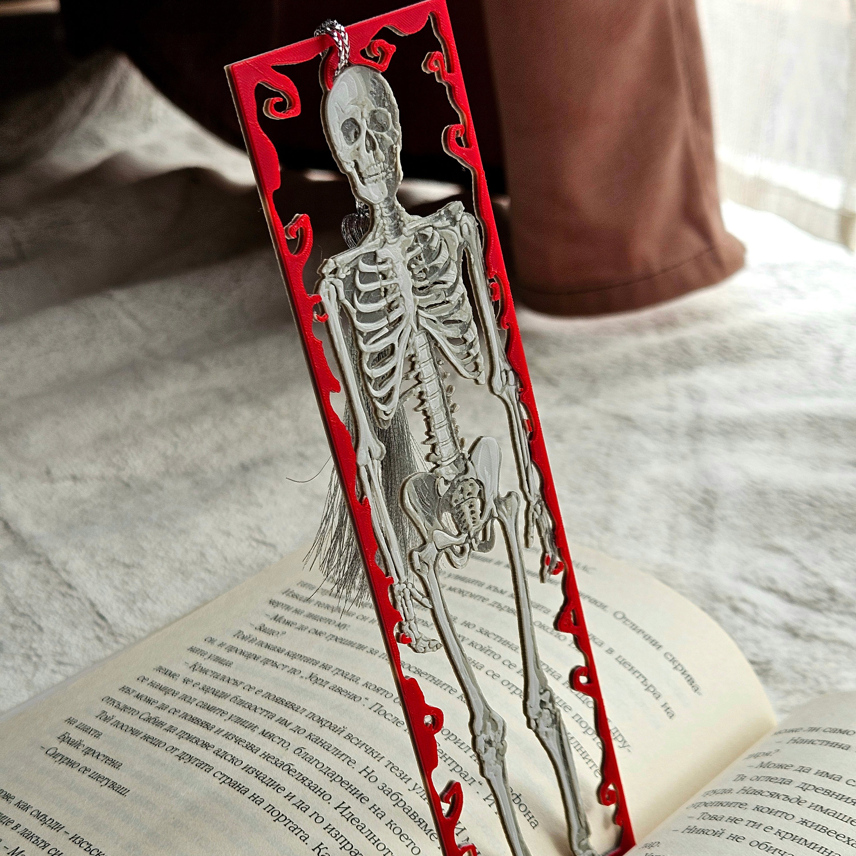 Skeletal design bookmark on an open book with a red decorative border.