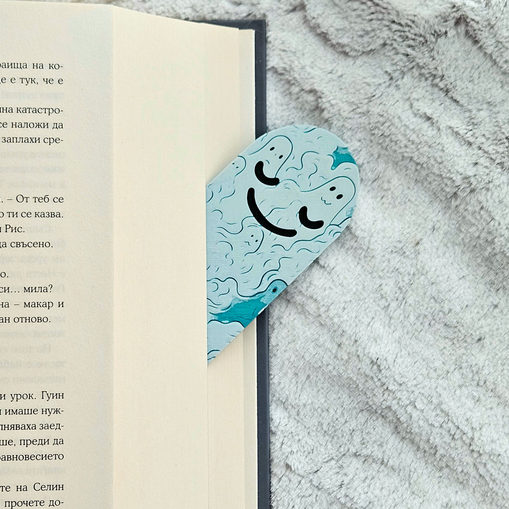 Bookmark with a smiley face design on a book lying on a textured surface
