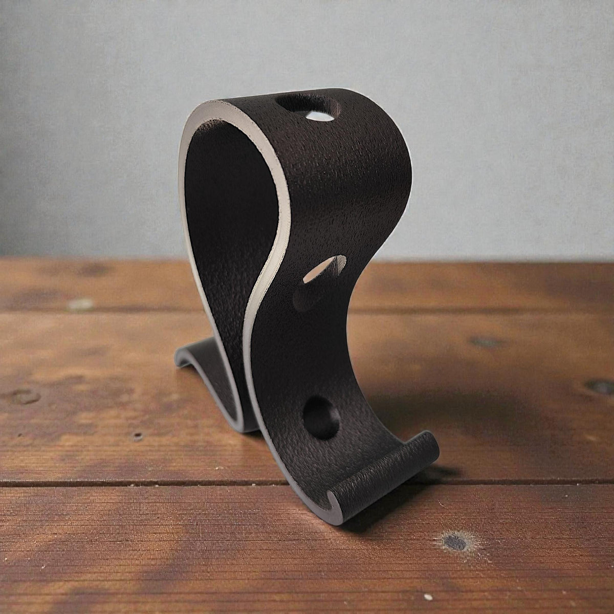 Black S-curve stand from the side, showing the holes for the tube