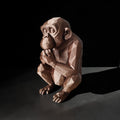 Stone sculpture of a monkey holding a coconut on a dark background