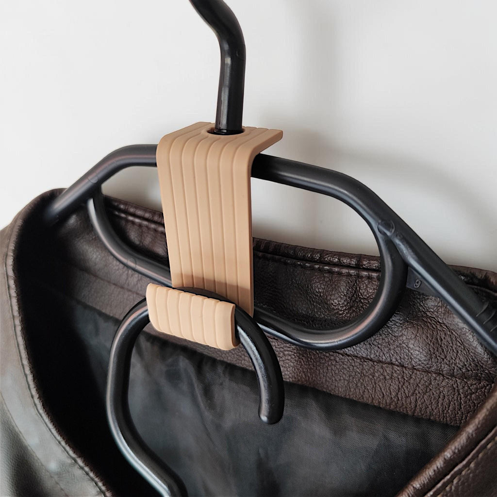 Brown hanger connector hook joining two hangers, holding a leather jacket