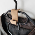 Brown hanger connector hook joining two hangers, holding a leather jacket