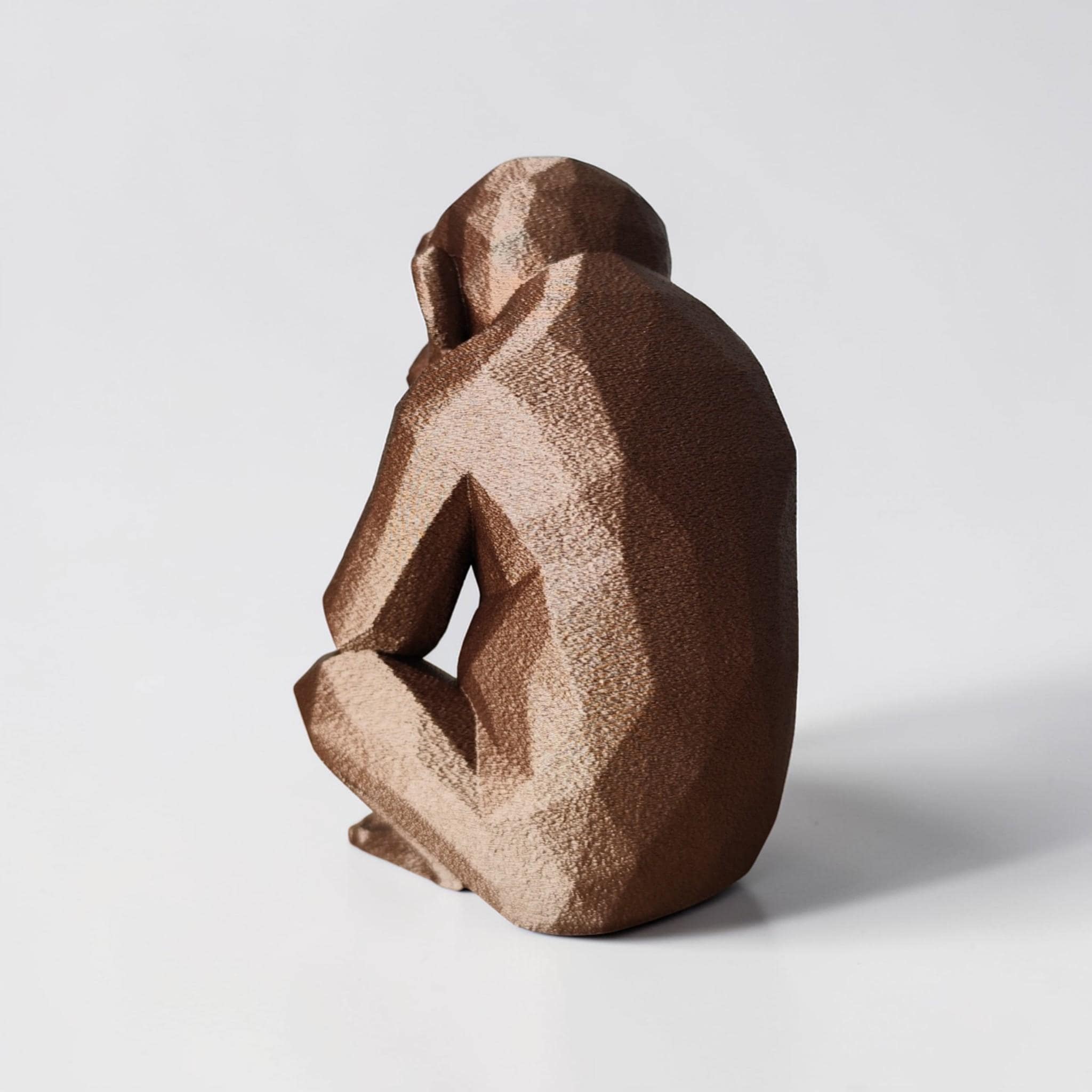 Brown ceramic monkey figurine on a light gray background