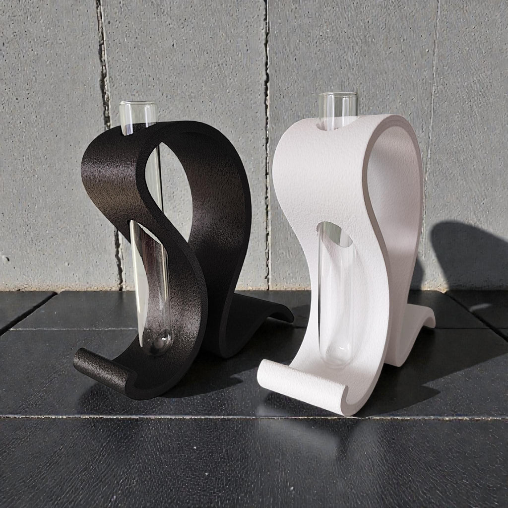 Black and white S-curve vases side by side with their glass tubes