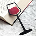 Black wine glass bookmark with red wine lying on an open book