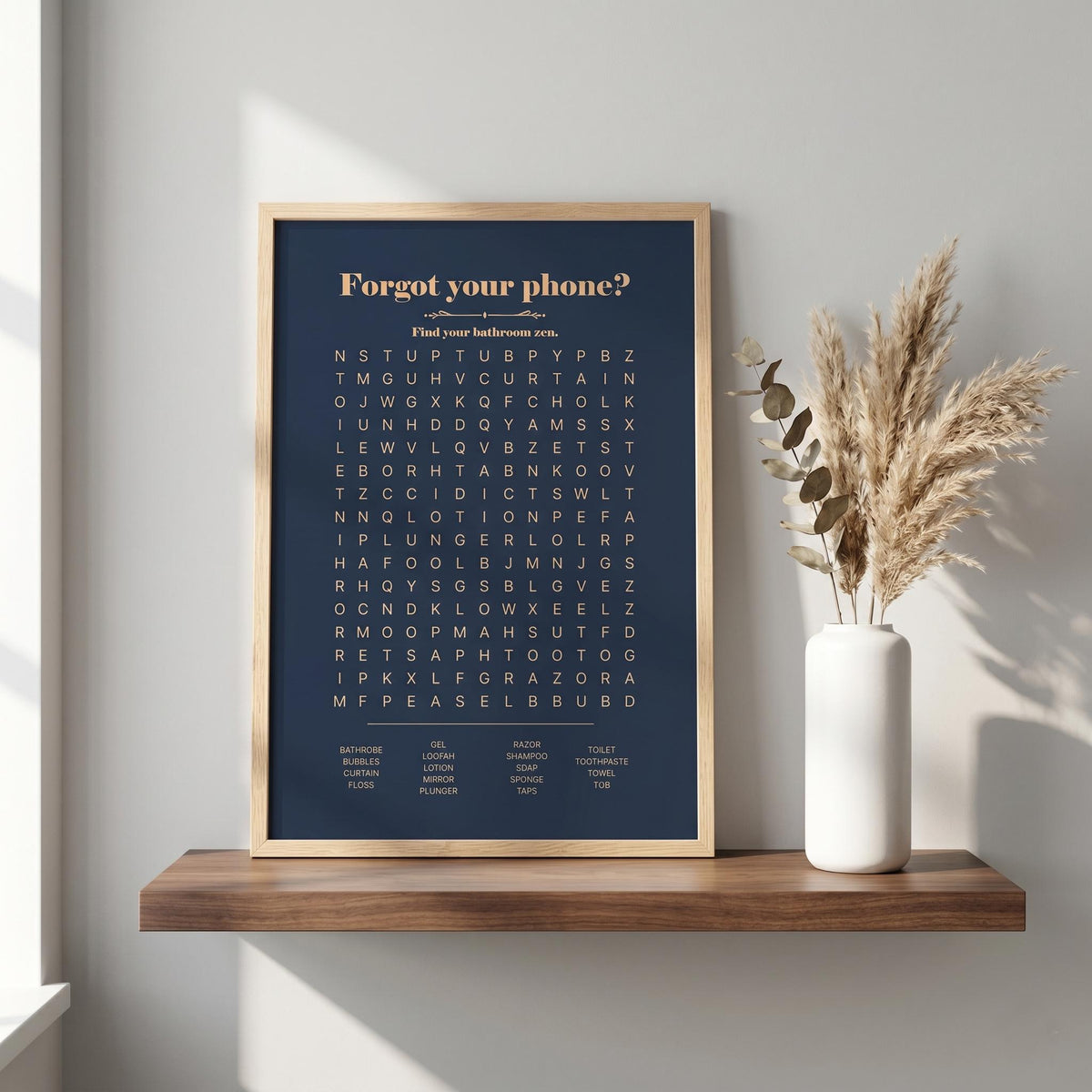 Navy bathroom word search print in a wood frame on a shelf