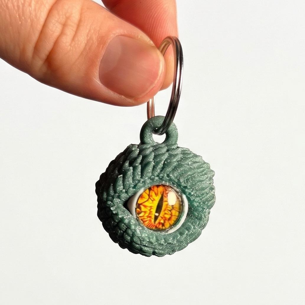 Green textured keychain with a circular orange and yellow design held by a hand against a white background